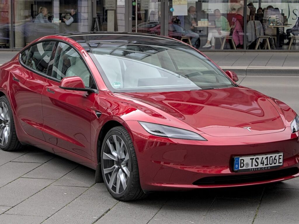 электромобиль tesla красного цвета на городской улице